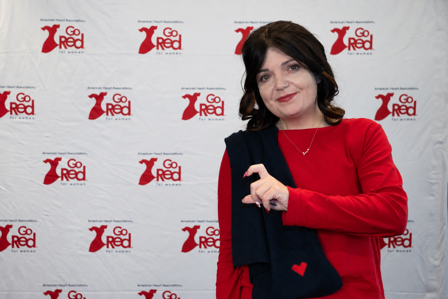 Jennifer Lentini wearing red and a black scarf with a red heart at a Go Red for Women event