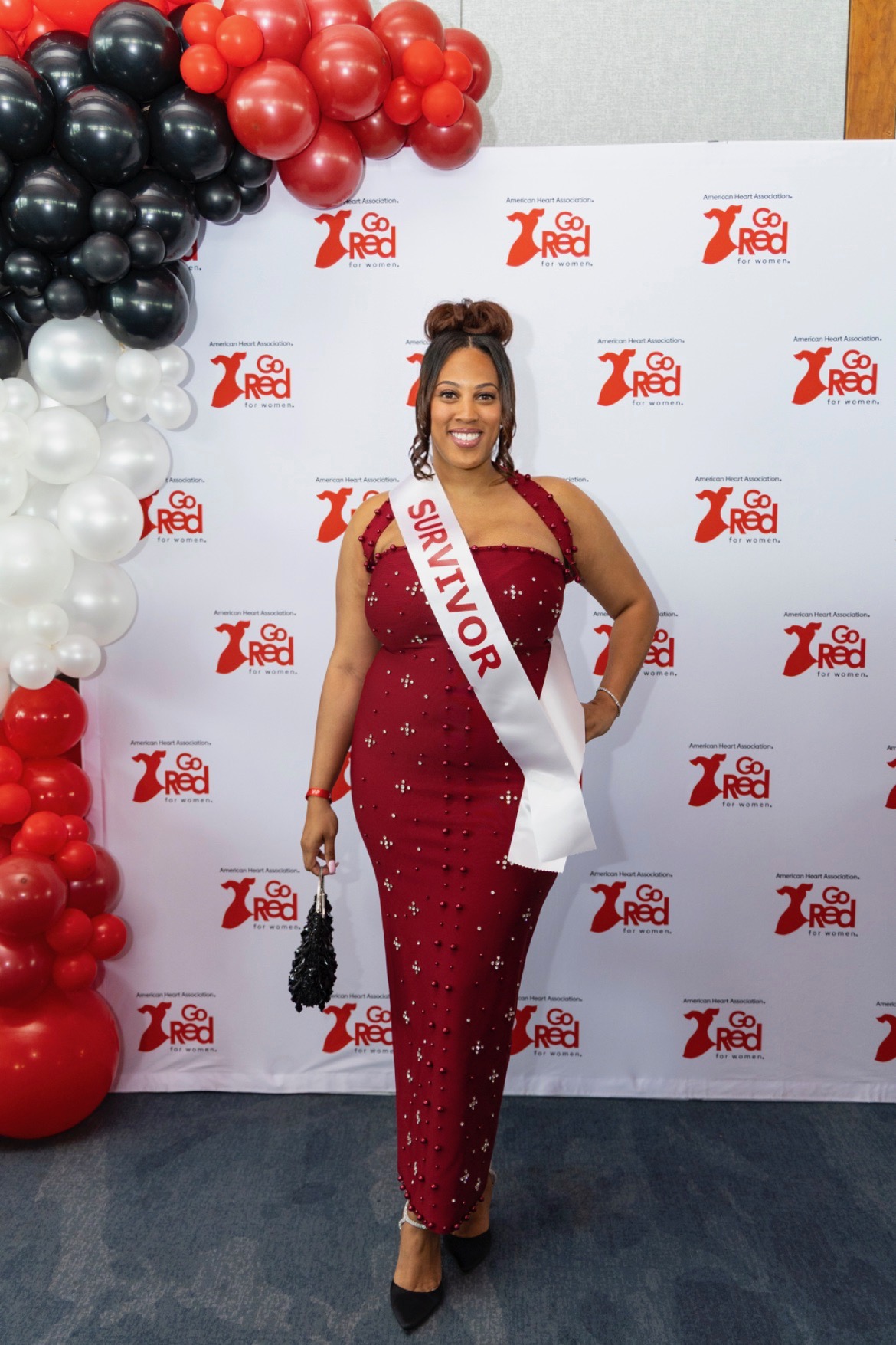 Phaleya Burnside wearing a burgundy gown and Survivor sash at a Go Red for Women event
