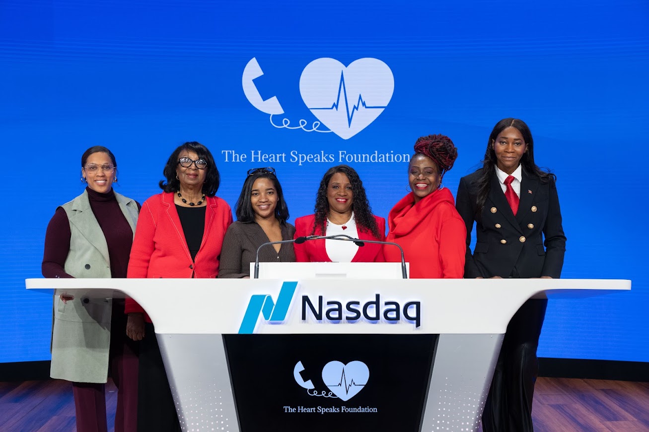 Sharon Bond and five fellow attendees at the Nasdaq podium beneath The Heart Speaks Foundation logo
