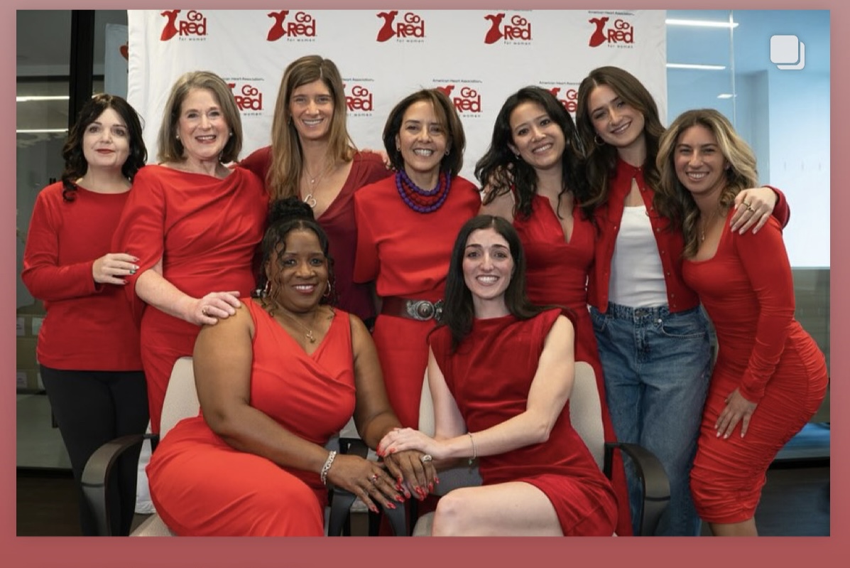 Nine women in red posing together in front of a Go Red for Women backdrop
